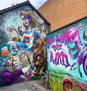 a mural on the side of a building covered in graffiti at The Rabbit Hole in Glastonbury