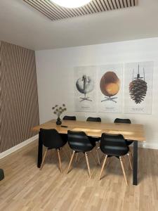 a wooden table with black chairs in a room at Just Sleep Delux in Brande