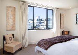 sypialnia z dużym oknem, łóżkiem i krzesłem w obiekcie Marine Square Luxury Suites w mieście Hermanus