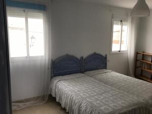 1 dormitorio con 1 cama azul y 2 ventanas en Casa COMPARTIDA Algarrobo, en Algodonales