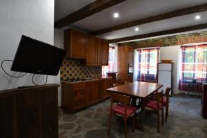 a kitchen with a table and a tv on the wall at Il Rustico in Ronco Canavese