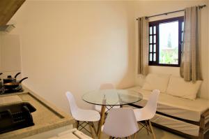 a small living room with a glass table and white chairs at Vila Lorenzi & Apartamentos in Ubatuba +13 photos