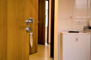 una puerta con llave en una habitación con nevera en Vila Lorenzi - Apartamentos, en Ubatuba