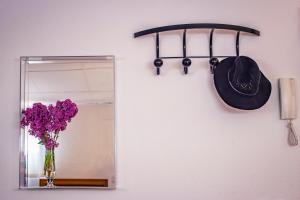 um espelho e um chapéu e um vaso de flores roxas em attic 27 em Villanueva de los Infantes