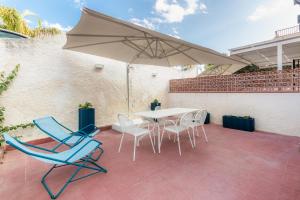 eine Terrasse mit einem Tisch, Stühlen und einem Sonnenschirm in der Unterkunft La Maiolica in Noto Marina