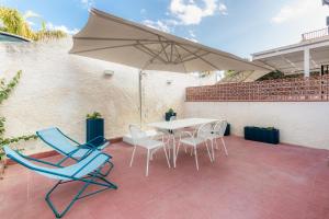 un patio con mesa, sillas y sombrilla en La Maiolica, en Marina di Noto