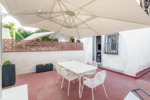 una mesa blanca y sillas bajo una sombrilla en un patio en La Maiolica, en Marina di Noto 23 fotos más