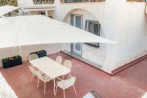 a white table and chairs under a large umbrella at La Maiolica in Noto Marina