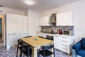 a kitchen with white cabinets and a wooden table at La Maiolica in Noto Marina