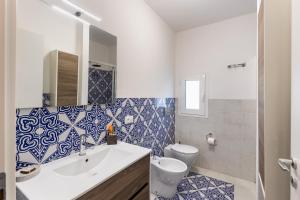 a bathroom with a sink and a toilet with blue and white tiles at La Maiolica in Noto Marina