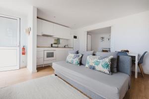 Una sala de estar con un sofá y una cocina. en O Clube, en Porto da Cruz