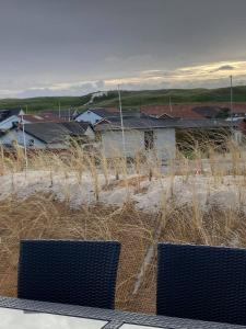 two chairs sitting on top of a beach with houses at Bakkebo in Hvide Sande