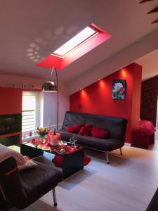 a living room with a black couch and a red wall at Rožu romantika in Cēsis