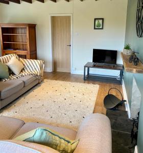 a living room with a couch and a television at Johnstonebridge Cottage in Johnstonebridge