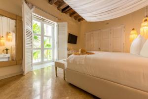 sypialnia z dużym białym łóżkiem i oknem w obiekcie Casa Diluca Cartagena Hotel Boutique w mieście Cartagena de Indias