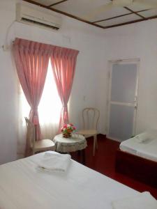 a room with two beds and a table and a window at Midland Hotel Rooms Kanampella in Kananpella