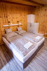 Cama grande en habitación con paredes de madera en Volcz Családi Birtok, en Ajka