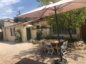 a table with an umbrella in front of a house at Maisonnette proche des calanques , les Bruyères in Marseille