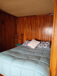 a bedroom with a large bed with wooden walls at lotus shared-house in Puerto Montt