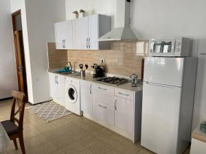 a kitchen with white cabinets and white appliances at Sarahs Kite Vivienda Vacacional en Playa del Burrero in Playa del Burrero