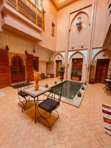 einen großen Innenhof mit einem Tisch, Stühlen und einem Pool in der Unterkunft Riad Mazaya in Marrakesch