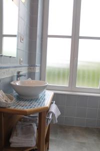 uma casa de banho com uma tigela sobre uma mesa e duas janelas em Manoir de la Roche Torin, The Originals Relais (Relais du Silence) em Courtils