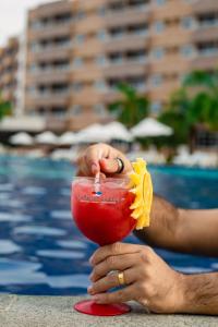 a person holding a drink in front of a pool at Grand Lençóis Flat in Barreirinhas