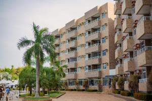 a building with a palm tree in front of it at Grand Lençóis Flat in Barreirinhas