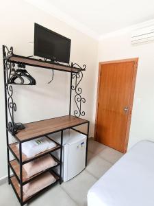 een kamer met een televisie op een plank en een deur bij Pousada Nossa Senhora Aparecida in Águas de São Pedro