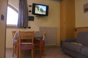 een eetkamer met een tafel en een tv aan de muur bij Snowflake Apartment in Livigno