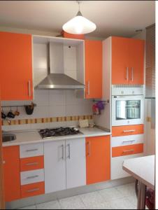 una cocina naranja y blanca con armarios blancos en Disfruta Granada,incluso con tu mascota Parking, en Granada