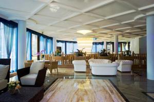 リモーネ・スル・ガルダにあるHotel Alexanderの白い椅子とテーブル、窓が備わる広い客室です。