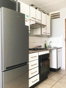 eine Küche mit einem schwarzen Kühlschrank und weißen Schränken in der Unterkunft Smart Studio with Netflix and no load shedding in Pretoria