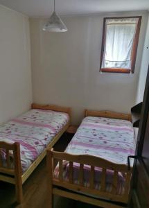 two beds in a small room with a window at La Petite Jeannette in Lans-en-Vercors