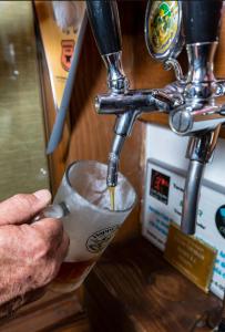 a man is holding a cup under a tap at Cinco Ríos Lodge in Coihaique