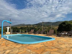 a swimming pool on a patio with mountains in the background at Pousada Império de Minas in Capitólio