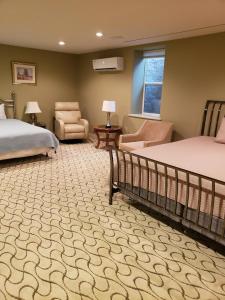 1 dormitorio con 2 camas, silla y ventana en Mill Creek Gardens, en Winamac