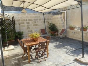 un patio con mesa de madera y sillas debajo de una tienda de campaña en Appartamenti "Il Delfino", en Lecce
