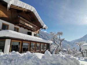 un edificio cubierto de nieve junto a un montón de nieve en Landgasthof Steiner, en Matrei in Osttirol