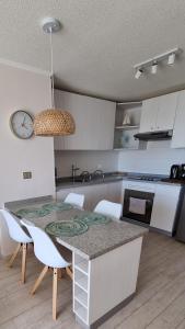 eine Küche mit einem Tisch, Stühlen und einer Uhr in der Unterkunft Relajo y tranquilidad a pasos del mar in La Serena