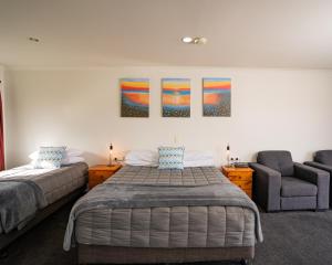 a bedroom with two beds and a chair at Alexandra Heights Motel in Alexandra