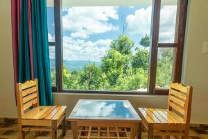 a room with two chairs and a table and a large window at Kasar wonder hill homestay in Almora