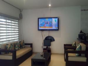uma sala de estar com um sofá e uma televisão na parede em Casa de Huespedes Villa Hermosa em La Vega