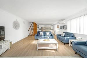 a living room with blue couches and a table at Husky 56 Beachfront Villa's in Huskisson