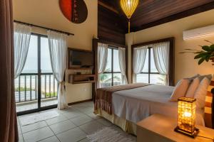 a bedroom with a bed and large windows at Pousada Olhos Verdes in Bombinhas