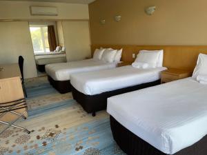 a hotel room with three beds in a room at Haven Marina Motel in Adelaide