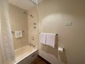 bagno con vasca, doccia e asciugamani bianchi di Haven Marina Motel a Adelaide Altre 67 foto