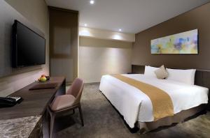 Pokój hotelowy z łóżkiem, biurkiem i telewizorem w obiekcie Park City Hotel - Hualien Vacation w mieście Hualian