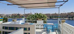 uma varanda com cadeiras azuis e vista para a água em Nuba Tod Abouda Guest House em Aswan