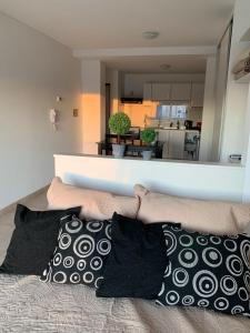 a bed with pillows on it with a kitchen in the background at Villa Ober Suites in Neuquén